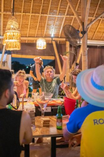 a group of people sitting around a table with their hands in the air at Clandestino Hostel Canggu in Canggu