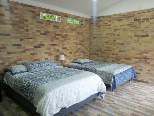 1 dormitorio con 2 camas y pared de ladrillo en FINCA AMBIENTE FAMILIAR EN LA GRAN VIA, en La Gran Via