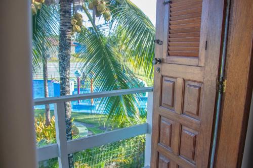 an open door to a balcony with a palm tree at Apto a 300m da praia AxéMoi in Porto Seguro