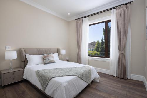 a white bedroom with a bed and a window at Vancouver Vacation Home in Richmond