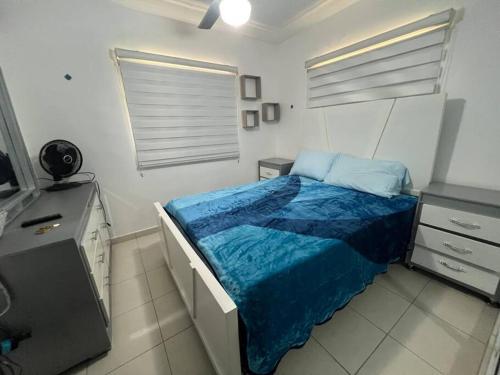 a bedroom with a bed with a blue blanket at Apartamento amueblado. in Santiago de los Caballeros