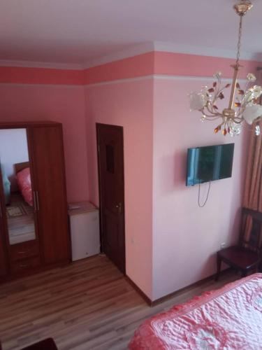 a bedroom with pink walls and a bed and a chandelier at Гостевой дом "Светлана" in Cholpon-Ata