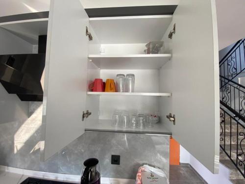 a kitchen with white shelves with glasses on them at Villa Ögreten in Aydın