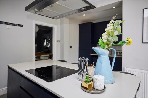 a kitchen with a blue vase with flowers in it at The Farnborough Wonder - Stunning 4BDR House with Garden in Farnborough