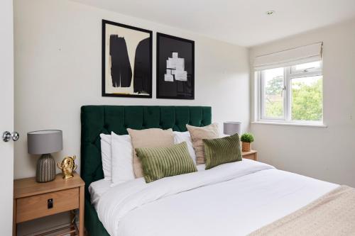 a bedroom with a large bed with a green headboard at The Farnborough Wonder - Stunning 4BDR House with Garden in Farnborough