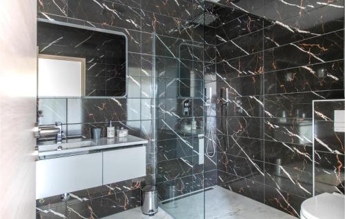 Baño de mármol negro con lavabo y espejo en Stunning Home In Labin With Kitchen, en Labin
