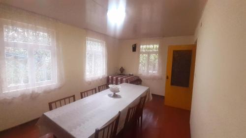 Cette chambre comprend une table, des chaises et des fenêtres. dans l'établissement Guest house VL, à Akʼori