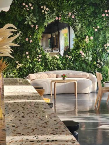 a living room with a couch and a wall of flowers at Phusira ภูศิรา กาญจนบุรี in Ban Tha Kilen (1)