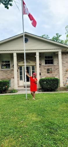 a woman holding a flag in front of a house at Niagara Falls Villa with Private pool, hottub, water view and Breakfast in Niagara Falls