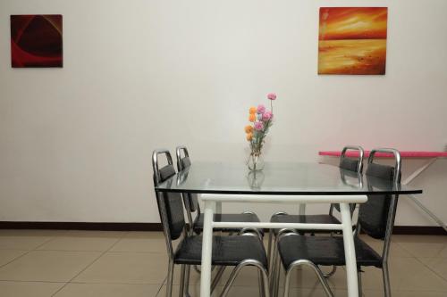 a table with chairs and a vase with flowers on it at Tropical Plaza Apt in Nadi