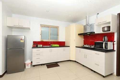 a kitchen with white cabinets and a refrigerator at Tropical Plaza Apt in Nadi