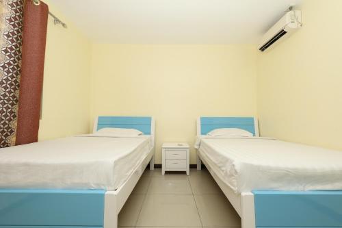 two beds in a room with white walls at Tropical Plaza Apt in Nadi