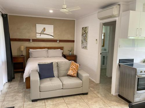 a bedroom with a bed and a couch and a kitchen at Marlo Hideaway in Marlo