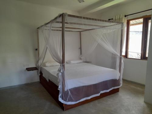 ein Schlafzimmer mit einem Himmelbett in einem Zimmer in der Unterkunft Mealanie's House in Unawatuna