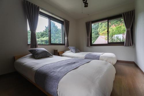 two beds in a room with two windows at YOICHI inn HAKONE in Hakone