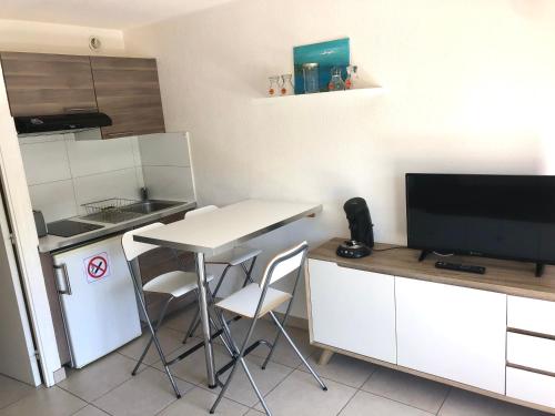 eine kleine Küche mit einem Tisch und einem TV in der Unterkunft Studio bord de mer Cavalaire in Cavalaire-sur-Mer
