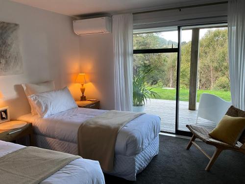 ein Hotelzimmer mit 2 Betten und einer Glasschiebetür in der Unterkunft Garden Apartment in Matakana