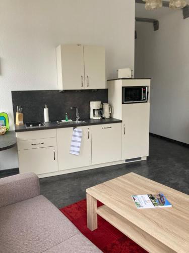 a kitchen with white cabinets and a coffee table at Haus Brandenburg in Stechlin