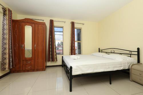 a bedroom with a bed and a dresser and window at Tropical Plaza Apt in Nadi