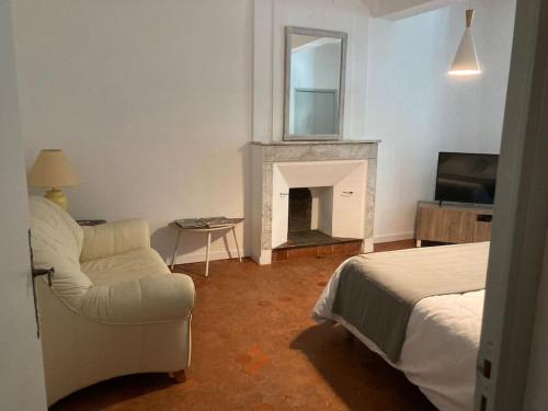 a bedroom with a bed and a chair and a fireplace at La Célestine in Valensole