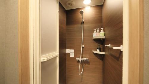 a shower in a bathroom with a wooden wall at Yutorelo Nikko in Nikko