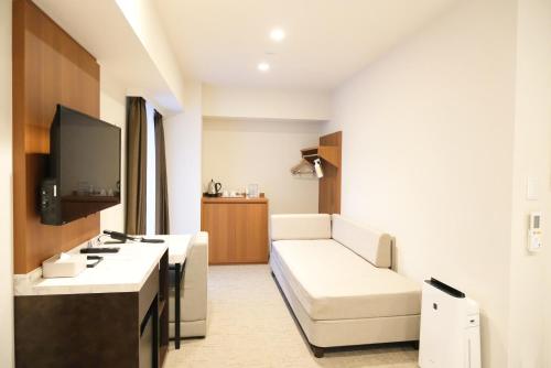 a living room with a couch and a tv at LUXCARE HOTEL in Osaka