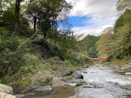 a river with a bridge on the side of a hill at 川辺-KAWABE-BBQ-川遊び-fishing in Hanno