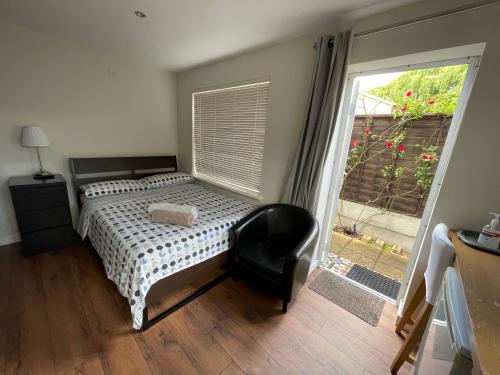 1 dormitorio con 1 cama, 1 silla y 1 ventana en Studio-2 Staines,Heathrow, London-own entrance, en Staines