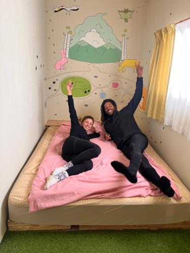 two girls laying on a bed with their hands in the air at TOTONOU Place in Asahikawa