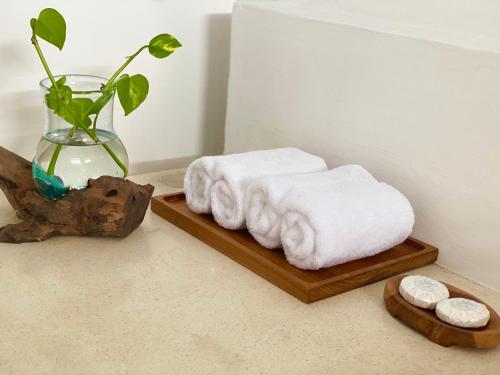 a couple of towels sitting on a wooden tray with a vase at Grey House Monkey Forest in Ubud