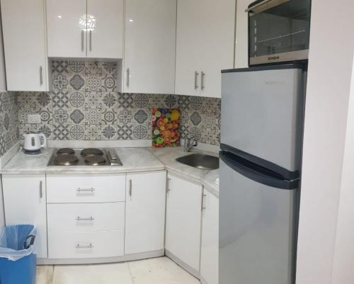 a small kitchen with white cabinets and a refrigerator at Tawaya sahl hashesh in Hurghada