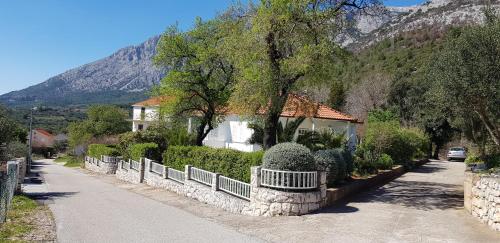 ein Haus mit einem Zaun vor einem Berg in der Unterkunft Casa Svjetlana in Orebić