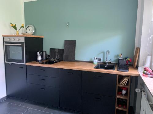 eine Küche mit schwarzen Schränken und einer hölzernen Arbeitsplatte in der Unterkunft Liebevolles Appartement-Erholung pur in Bad Sachsa in Bad Sachsa