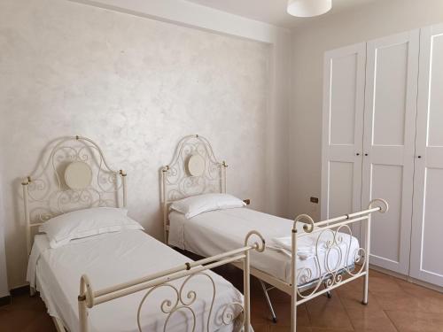 appartamento Alleria في لاتيرزا: سريرين في غرفة نوم بجدران بيضاء