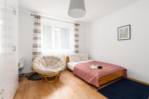 1 dormitorio con 1 cama y 1 silla en Spacious Family Apartment Promienista 1,5 km to Hala Arena Poznań by Renters en Poznan
