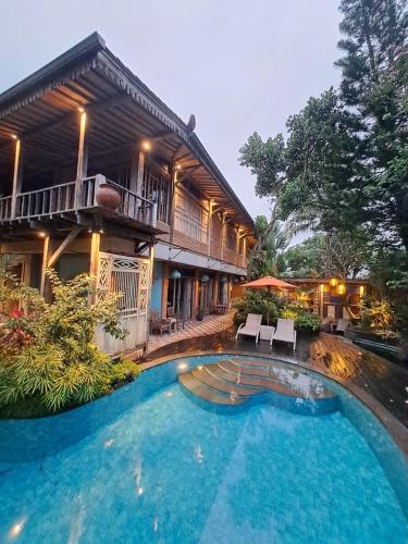 a house with a swimming pool in front of it at Ayu Dira Heritage House in Ubud