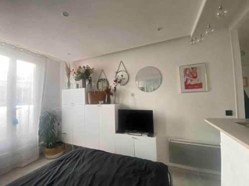 a living room with a tv on a white wall at Appartement studio proche Paris 14, Paris 15 in Malakoff