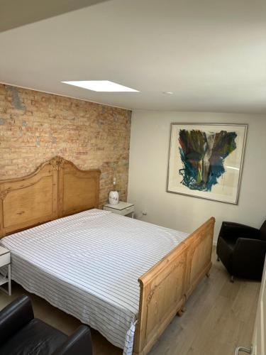 a bedroom with a wooden bed and a brick wall at Villa Holger in Skagen