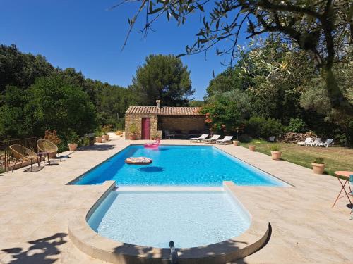 une piscine dans une cour avec une maison dans l'établissement Gîtes Mas des rochers - Romance tropicale avec Spa, au Beausset