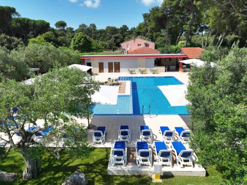 a swimming pool with lounge chairs next to a house at Mediterranean Village San Antonio in Biograd na Moru