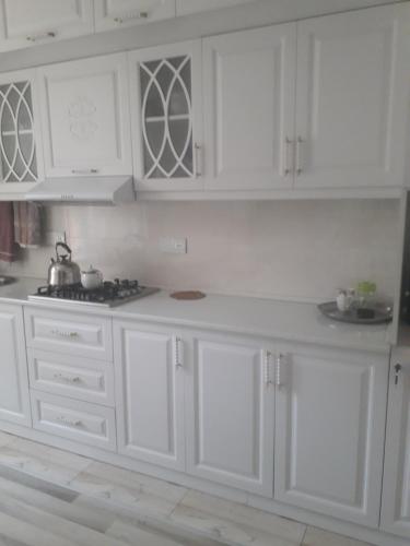 een witte keuken met witte kasten en een fornuis bij Apartment at Narimanov 151 in Ganja