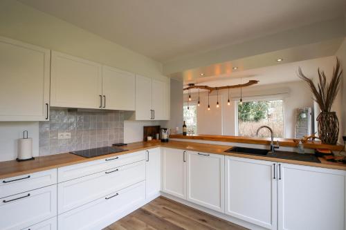 a kitchen with white cabinets and wooden counter tops at Villa De Strandjutter in Nieuwpoort