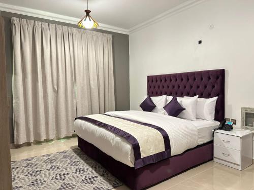 a bedroom with a large bed with a purple headboard at Sea Shore Hotel Apartment Khorfakkan in Khor Fakkan