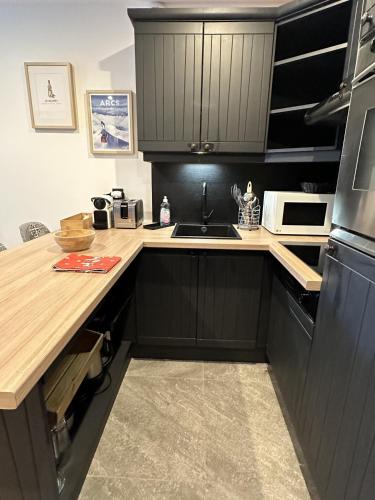 a kitchen with black cabinets and a counter top at Arcs 1950 Appartement prestige Ski InOut 6 pax in Bourg-Saint-Maurice