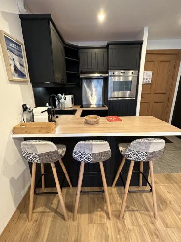 a kitchen with a wooden counter with two stools at Arcs 1950 Appartement prestige Ski InOut 6 pax in Bourg-Saint-Maurice