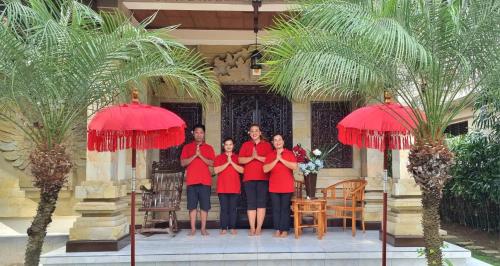 a family standing under red umbrellas in front of a house at Balinda Rooms & Villa in Lovina