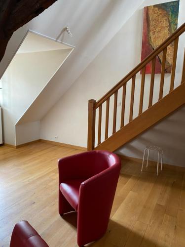 a red chair in a living room with a staircase at Loft duplex de charme 8 p plein centre in Lisieux