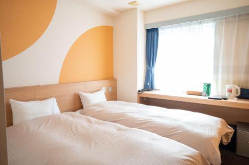 a bedroom with a white bed and a window at Hotel Raffinato Chitose in Chitose