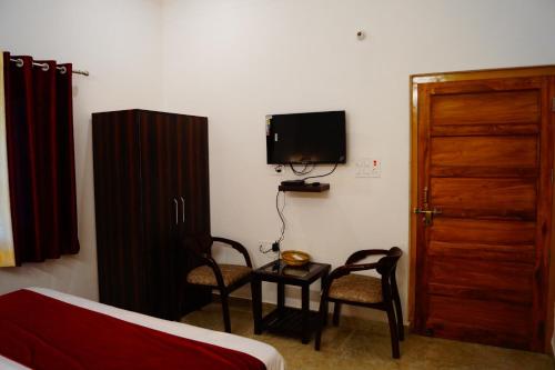 Zimmer mit einem Bett, 2 Stühlen und einem TV in der Unterkunft The Lake House by "Lake & woods" in Bhīm Tāl