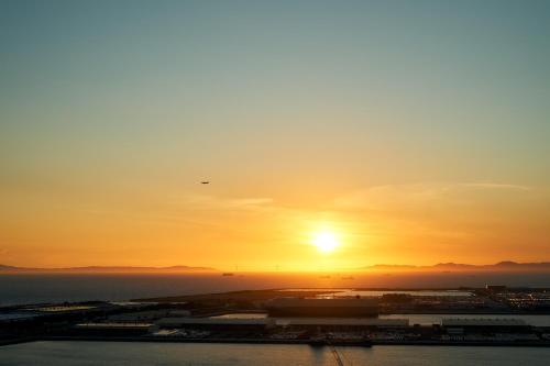 zachód słońca nad oceanem i słońce na niebie w obiekcie Kanku Izumiotsu Washington Hotel w mieście Izumiotsu